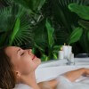 A woman relaxes in hot bath tub with soap foam